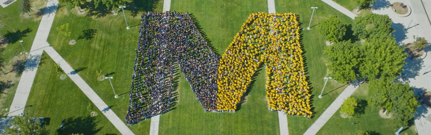 UC Merced Student Standing in the Shape of UC Merced Big M Logo
